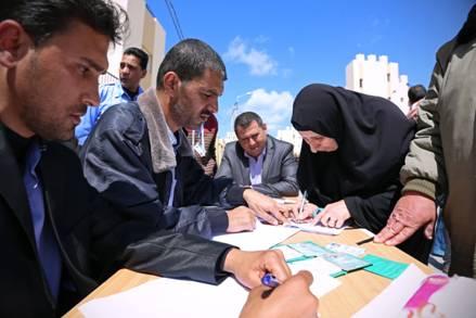 غالية عليان 63 عاما توقع على استلام مفتاح منزلها الجديد (تصوير تامر حمام)